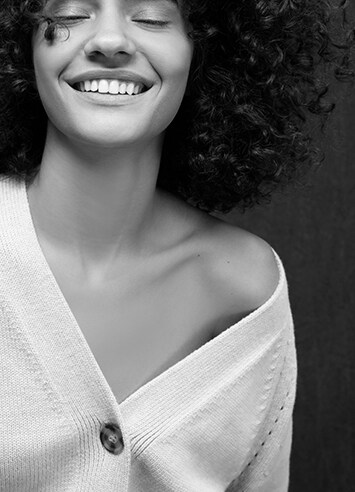 Black and white photo of a smiling woman wearing a blouse