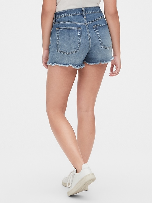 2 of 8 showing, with the color medium indigo of product High Rise Cheeky Denim Shorts with Raw Hem